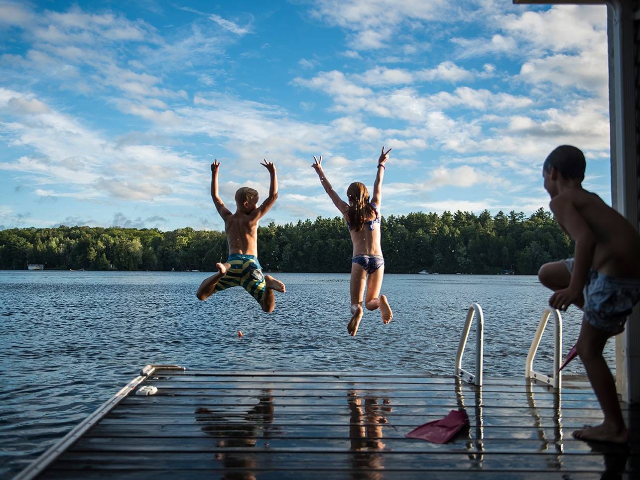 Kids jumping into the lake with their arms thrown up in joy!