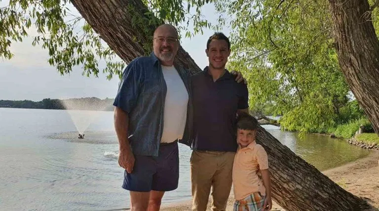 Family posing by a tree near a lake.